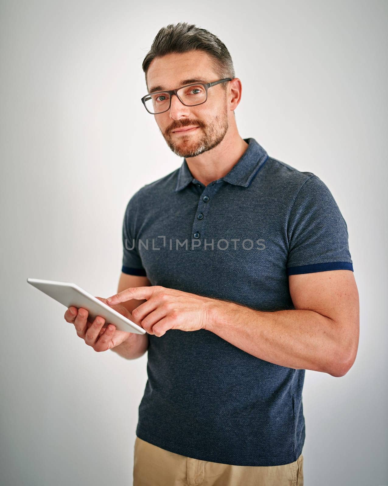 Touchscreen technology is the way to go. a man using a digital tablet against a gray background. by YuriArcurs