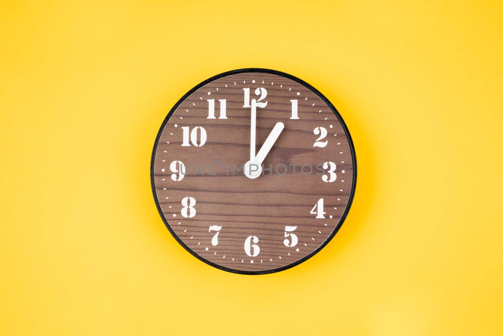 Retro wooden clock at 1 O' clock on yellow color background.