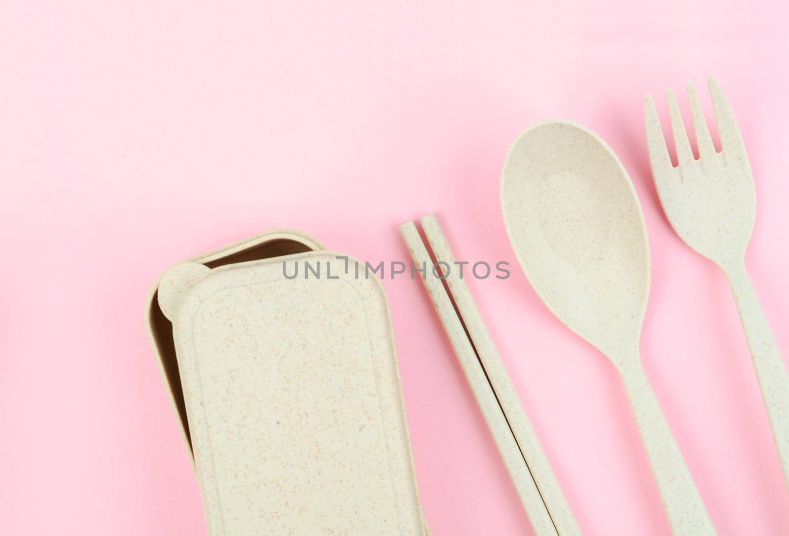 The Plastic spoons, forks and chopsticks set on pink color background. by Gamjai
