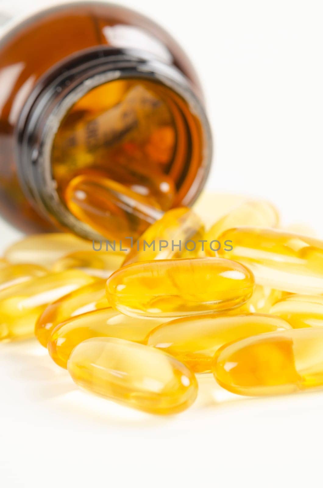 Fish oil capsules in a glass bottle on white background.