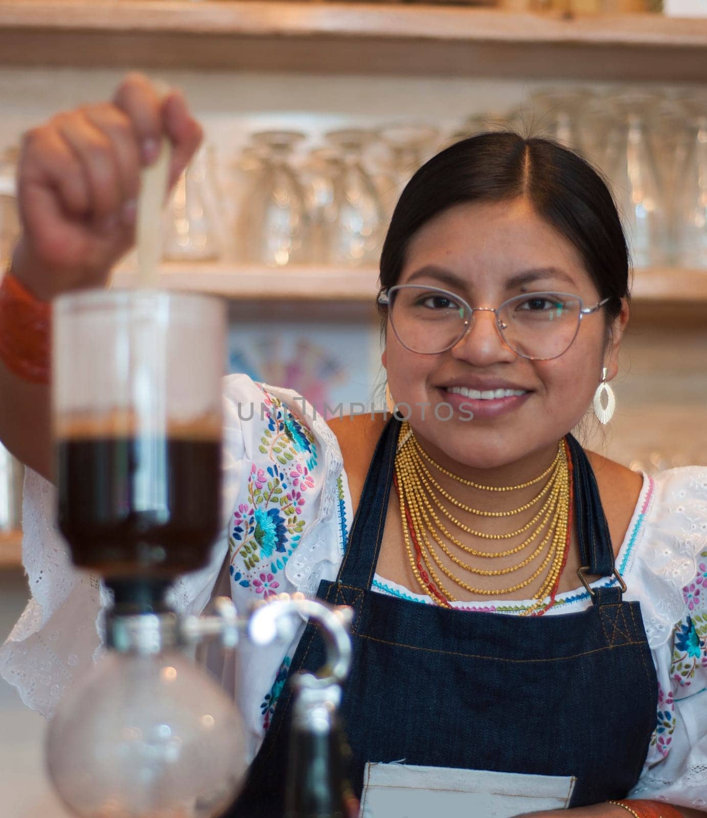 closeup of indian girl and barista making a coffee in a japanese coffee pot smiling and looking at camera. High quality photo