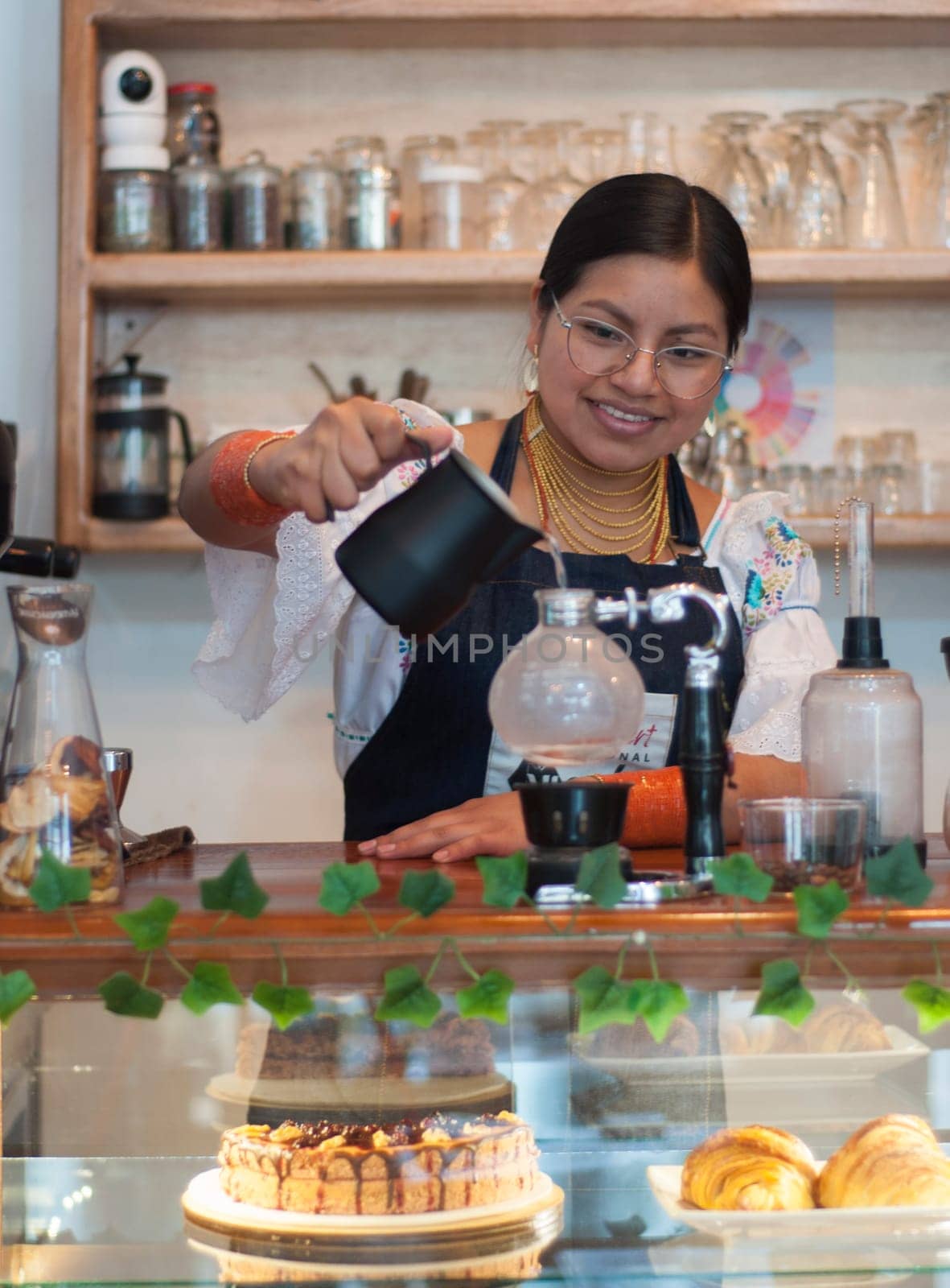 indian woman barista putting water in a japanese coffee pot to make an espresso inside a coffee shop. High quality photo