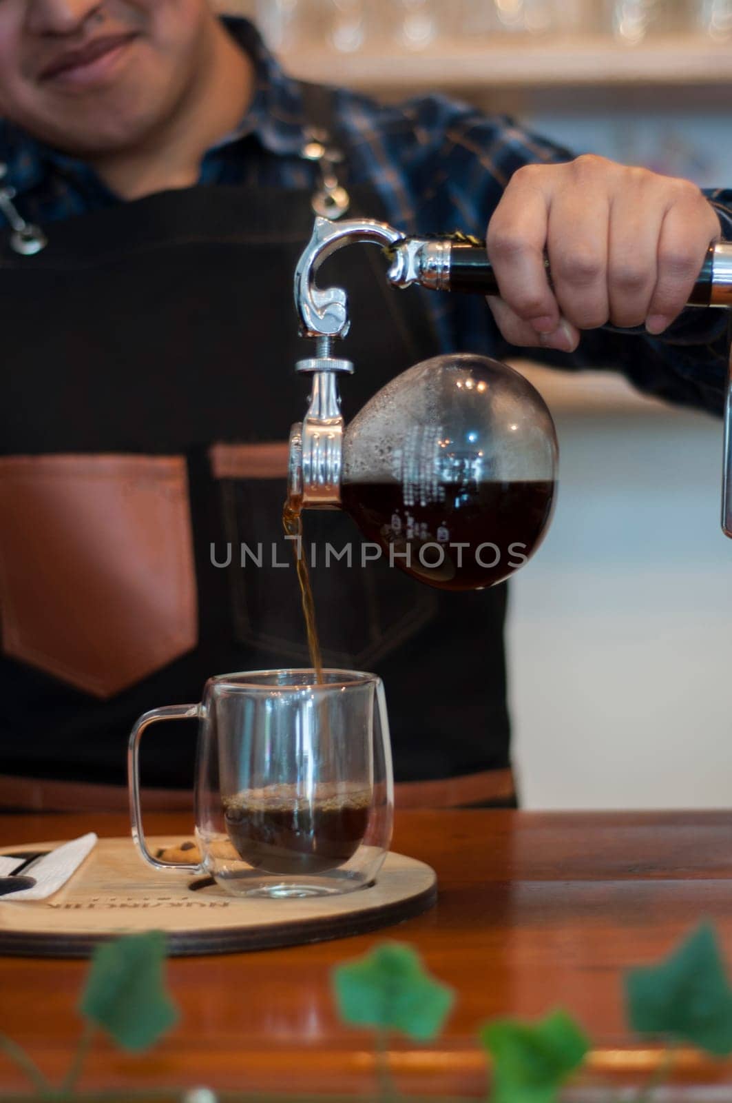 barista sirviendo un cafe expresso de una cafetera japonesa a un vaso para servir en una cafeteria. High quality photo