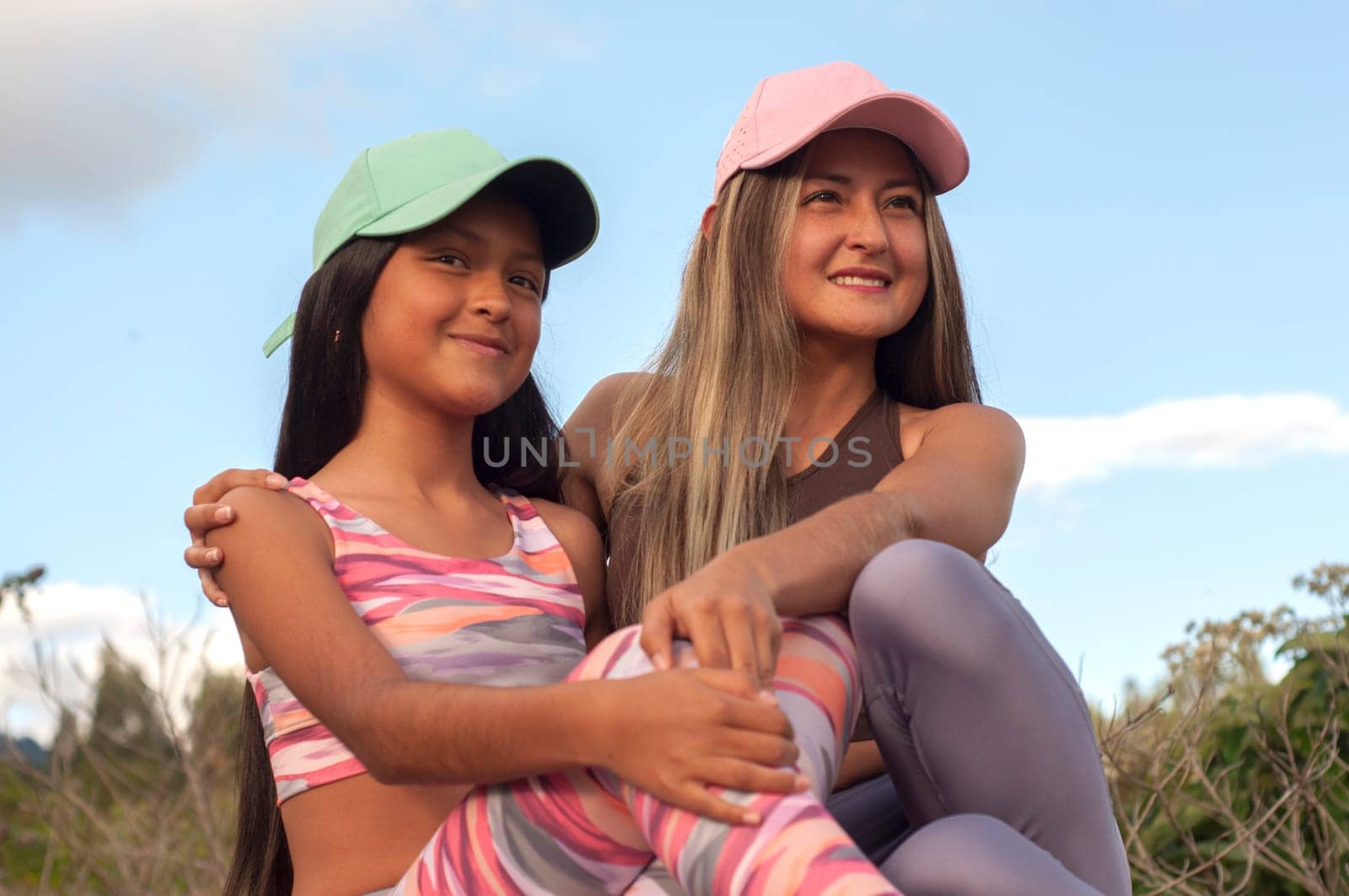 closeup of happy and joyful mom and daughter in caps looking at horizon in nature. High quality photo