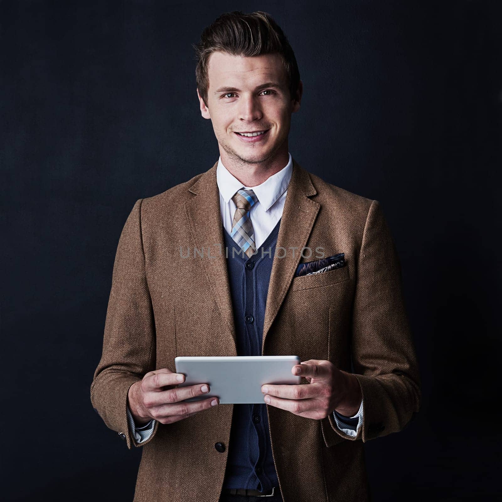 Technology only added to my success. Studio shot of a young businessman using his tablet against a dark background. by YuriArcurs