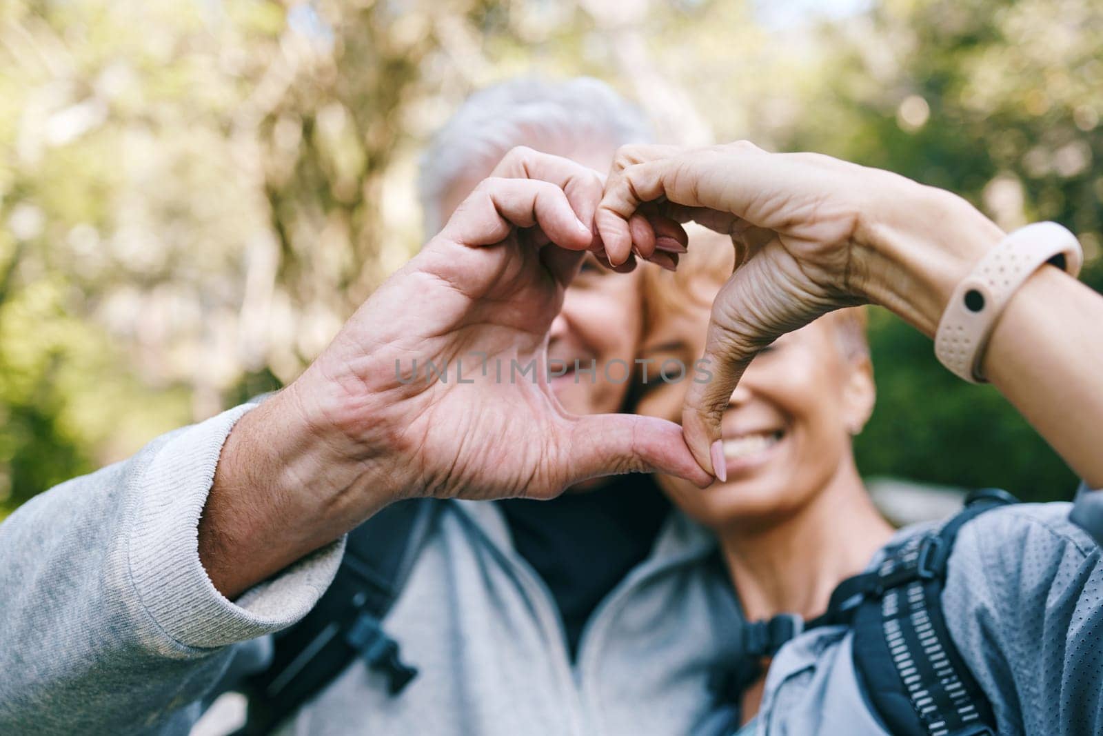 Heart, love hands and senior couple outdoors on vacation, holiday or hiking trip. Affection sign, romance emoji and elderly interracial couple, man and woman bonding together in nature on a hike