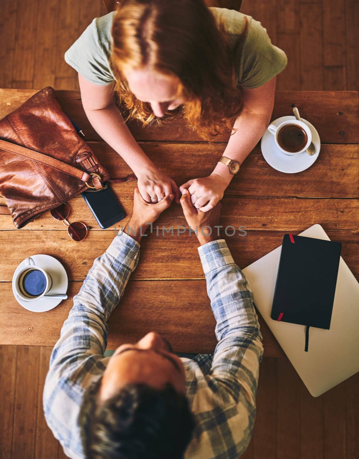 Couple holding hands, love and date at coffee shop on Valentines day, trust and care, wood table top view..People in cafe, support and respect with commitment . and together in relationship.