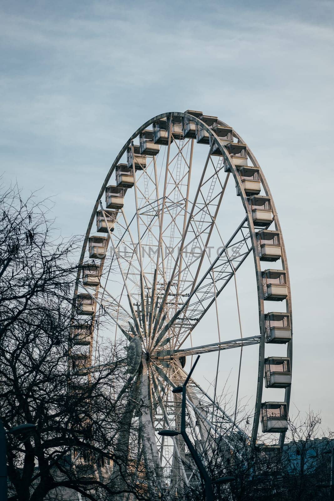 Enjoy a thrilling ride on the iconic ferris wheel among trees and the blue sky at the amusement park by apavlin