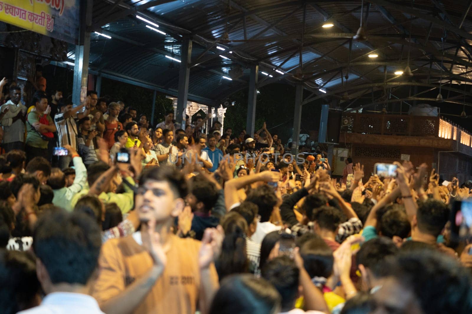Rishikesh, Uttarakhand - circa 2023 : huge crowd of people chanting and dancing at triveni ghat enjoy religious devotion as part of the ganga aarti ceremony in the evening