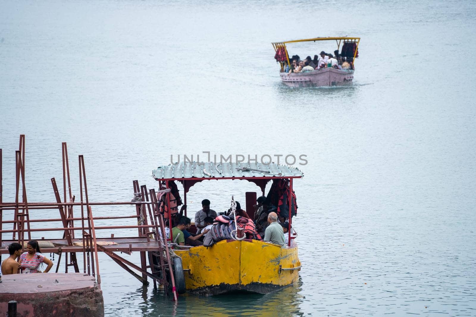 Rishikesh, haridwar, India - circa 2023: People boarding an old and broken ferry boat that runs across the river ganga shows the worn out and unsafe boats that tourists travel by