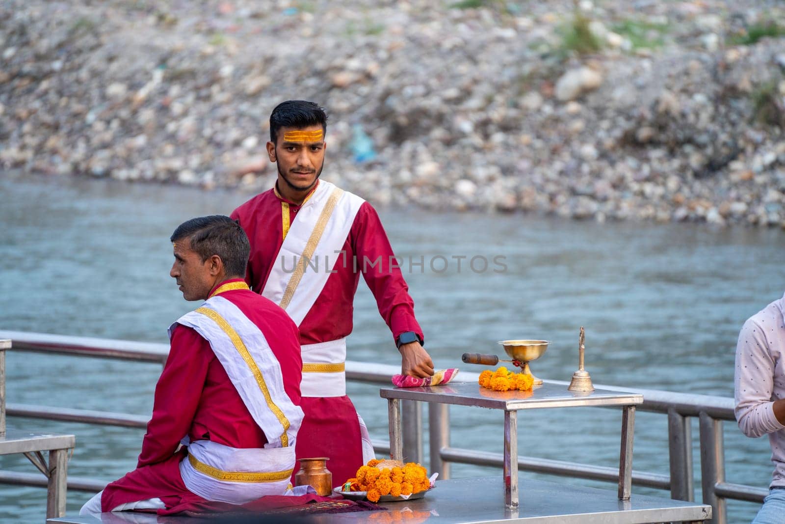 Rishikesh, Uttarakhand - circa 2023 : Group of priests preparing for the evening ganga aarti ceremony discussing the plan with their guru teacher who wears white on red