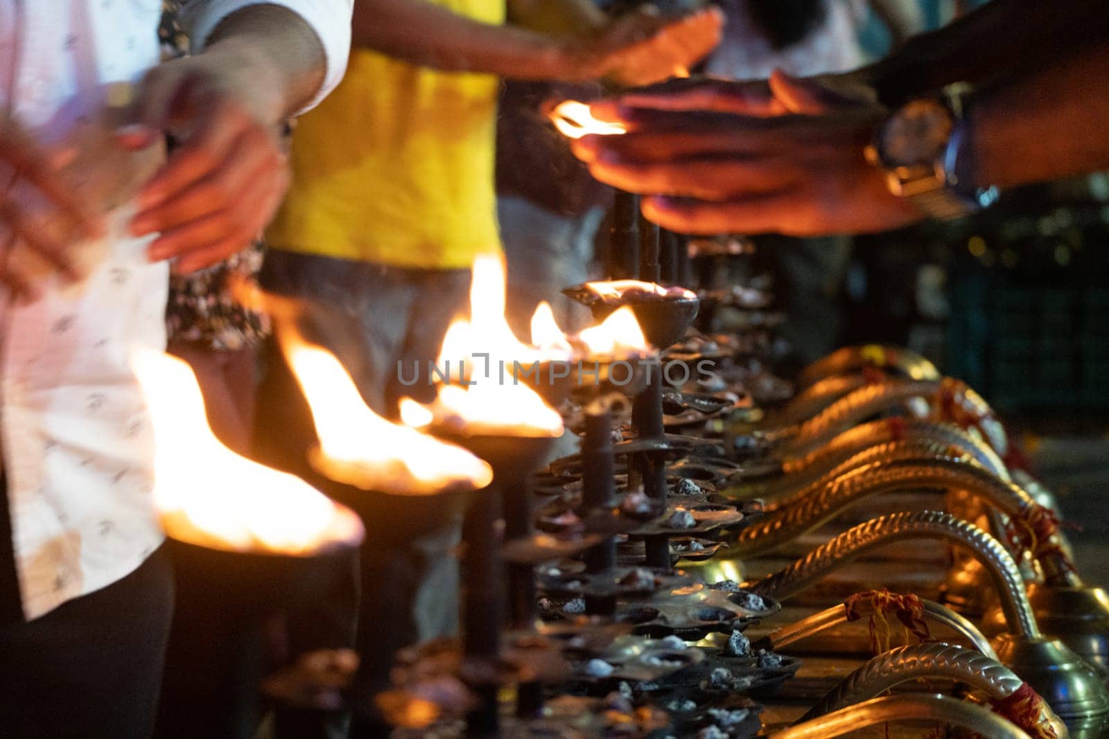 LIne of fire oil lamps on the ghat of ganga in rishikesh where people take blessings by passing their hands over the fire in Hinduism in India