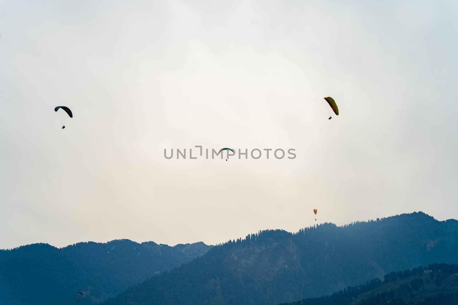 multipel parasailing gliders against sunset sky and mountains with copy space and bright colors showing freedom in hill station in India