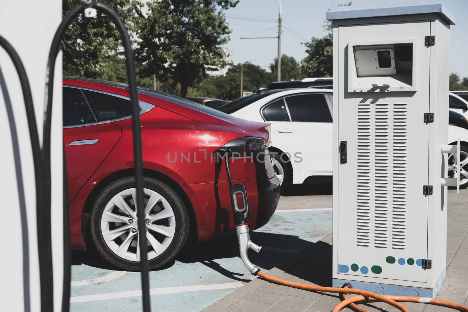 Charging modern electric car on the parking. Electric car charging on parking lot with electric car charging station on city street.