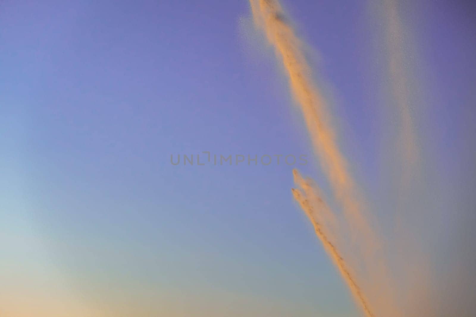 irrigation of a field against sky at sunset. irrigation system rain guns sprinkler on agricultural field.