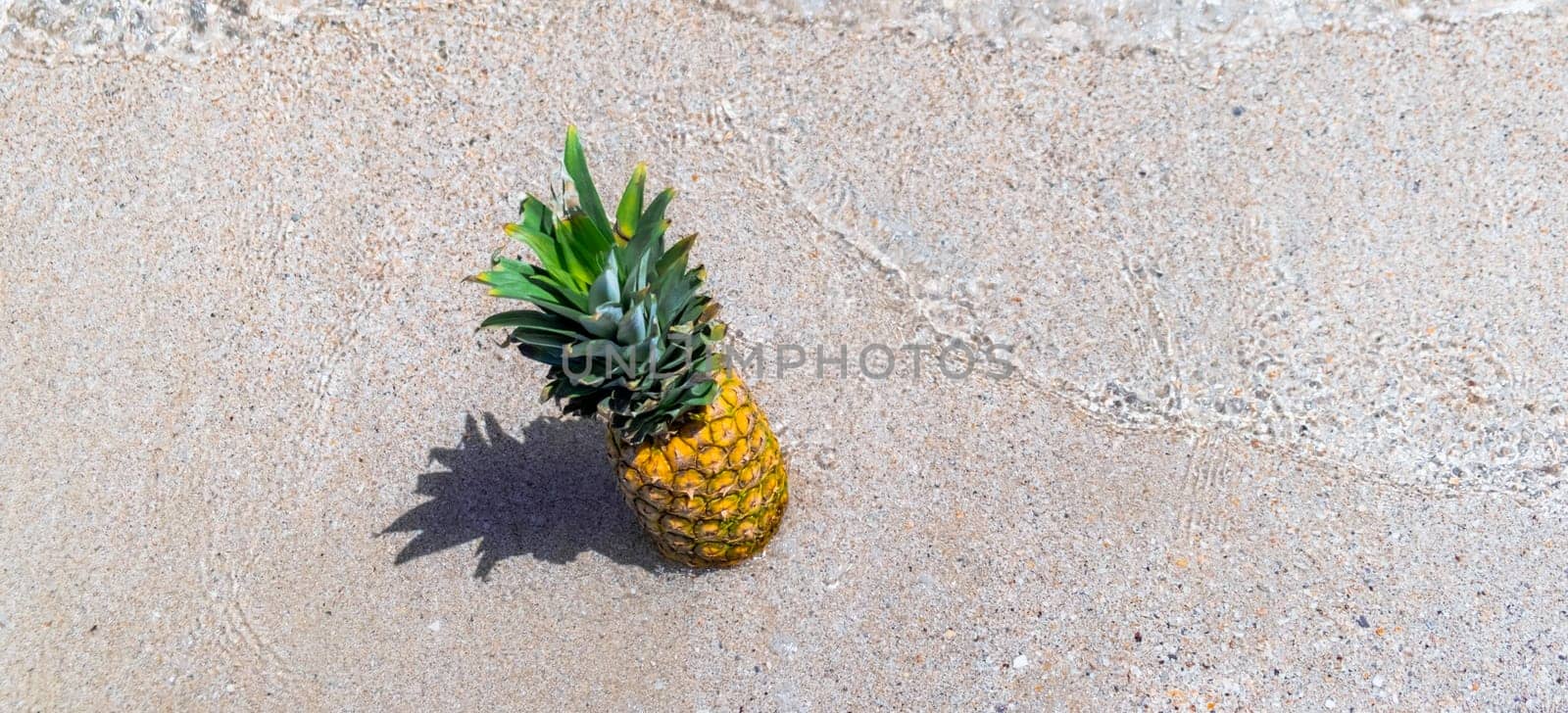 Fresh pineapple on the beach. Fruit in the sea waves. Summer vacation concept. by igor010