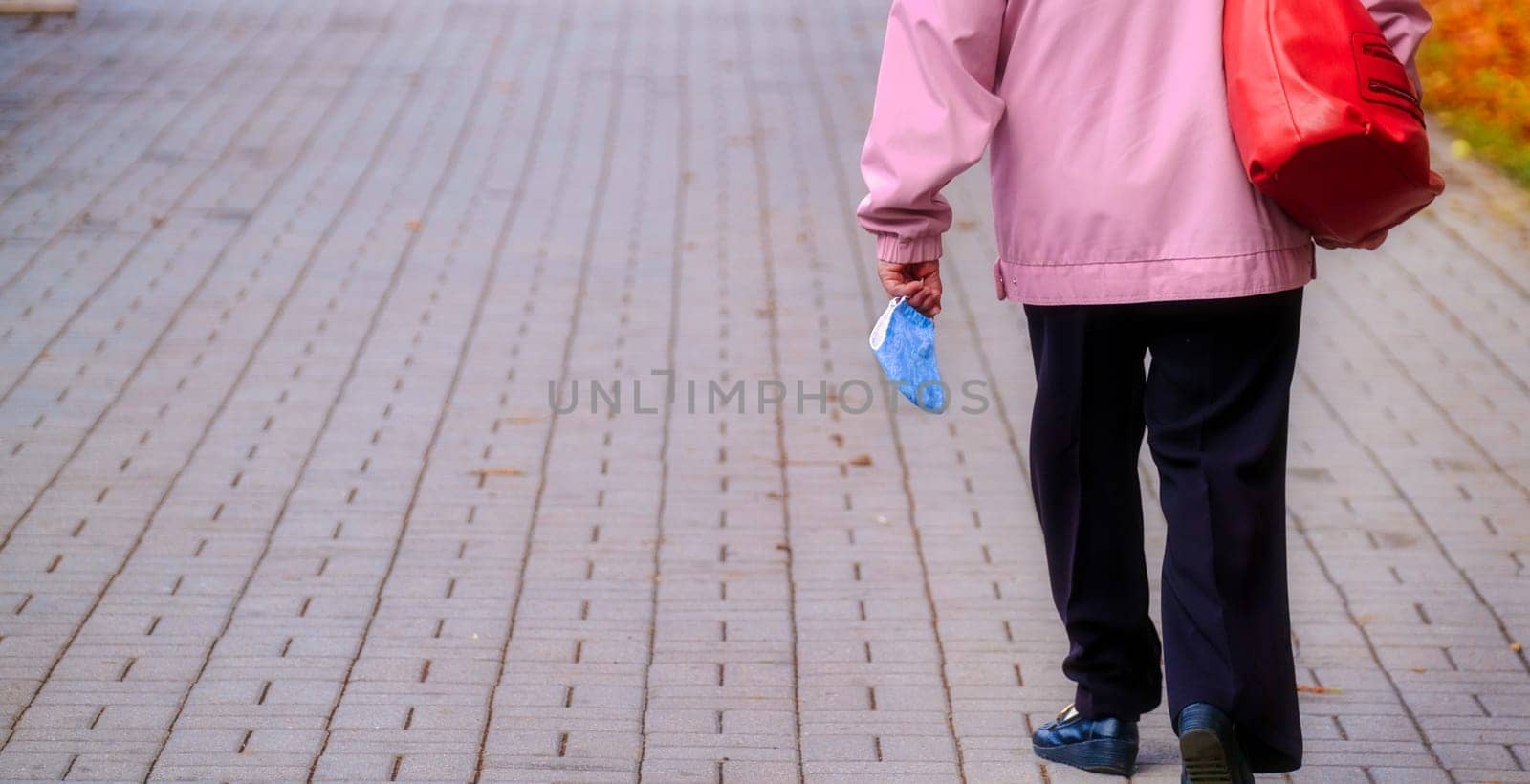 Woman walking on the street with protective face mask holding in hand. Woman take off protective mask protection of coronavirus. copy space