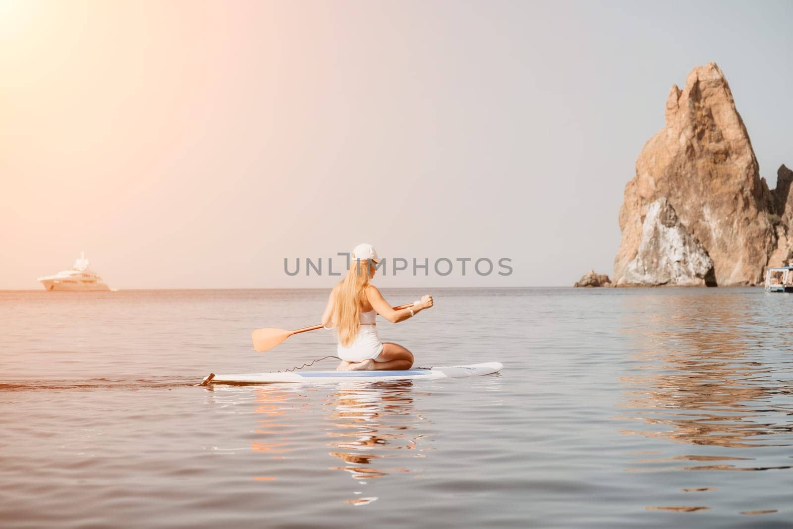 Close up shot of beautiful young caucasian woman with black hair and freckles looking at camera and smiling. Cute woman portrait in a pink bikini posing on a volcanic rock high above the sea