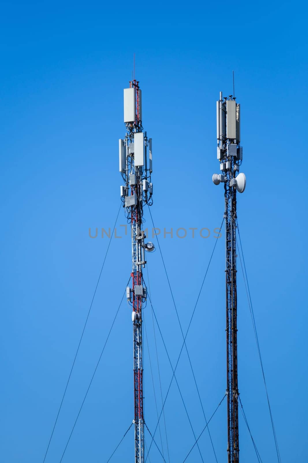 Technology of telecommunication GSM 5G,4G,3G tower. Cellular phone antennas on a building roof. Receiving and transmitting stations with blue skies on the background.