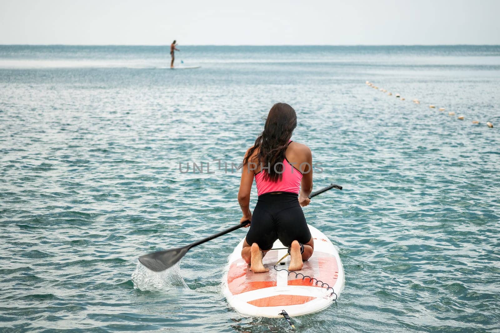 Sea woman sup. Silhouette of happy young woman in pink bikini, surfing on SUP board, confident paddling through water surface. Idyllic sunset. Active lifestyle at sea or river. Slow motion