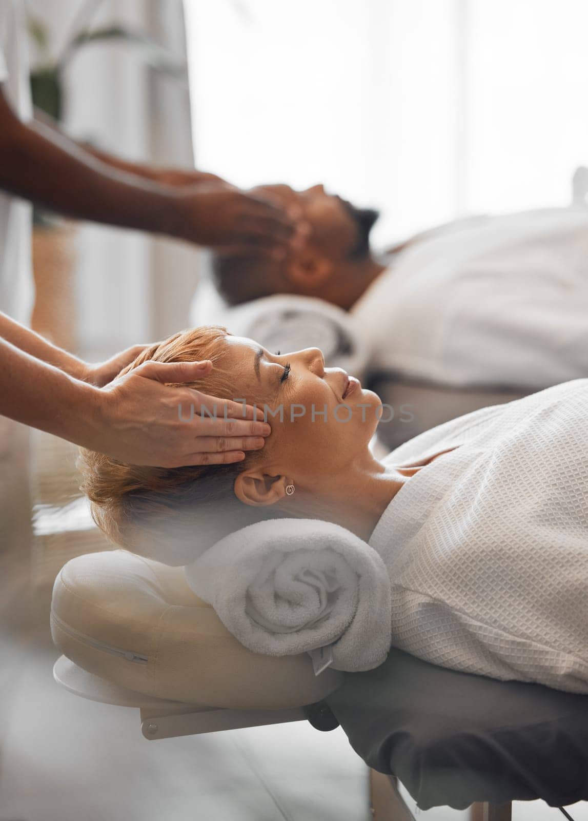 Hands, head and massage with a woman customer in a spa to relax for wellness or luxury. Face, beauty and therapy with a mature female customer and masseuse in a health clinic for stress relief by YuriArcurs