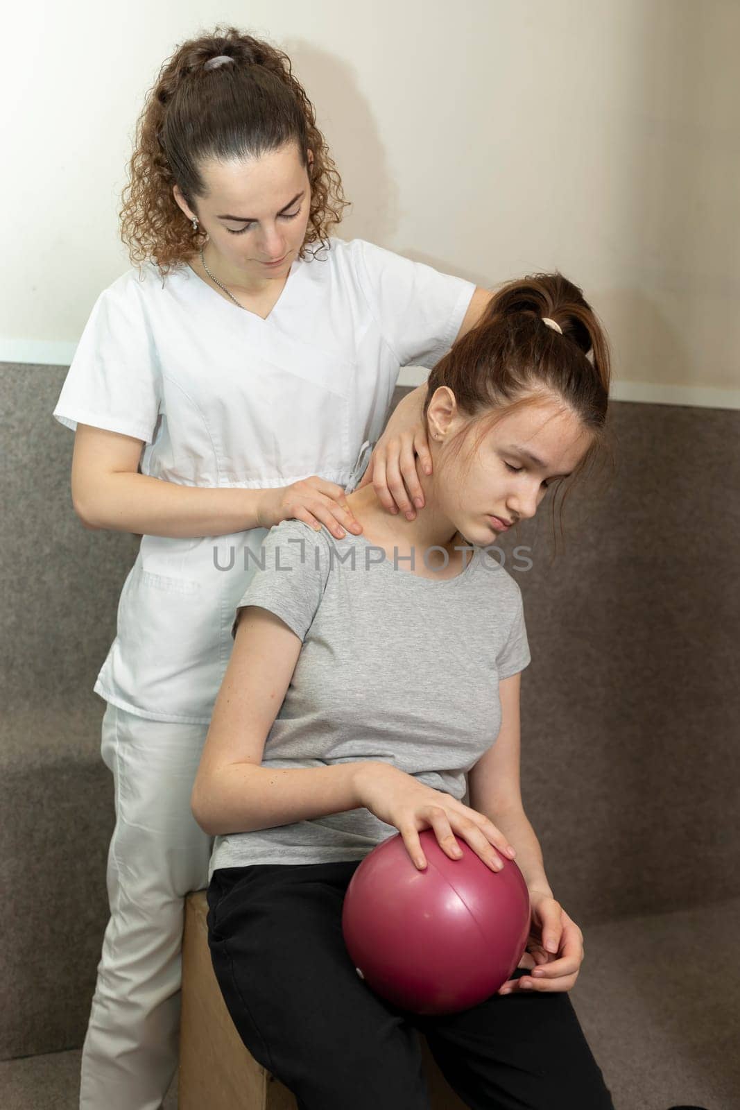 Physical Therapist Does Neck Massage To Child With Disability. Muscle Relaxation, Stretching After Physical Exercises With Ball. Health Support, Rehabilitation In Gym. Vertical plane by netatsi