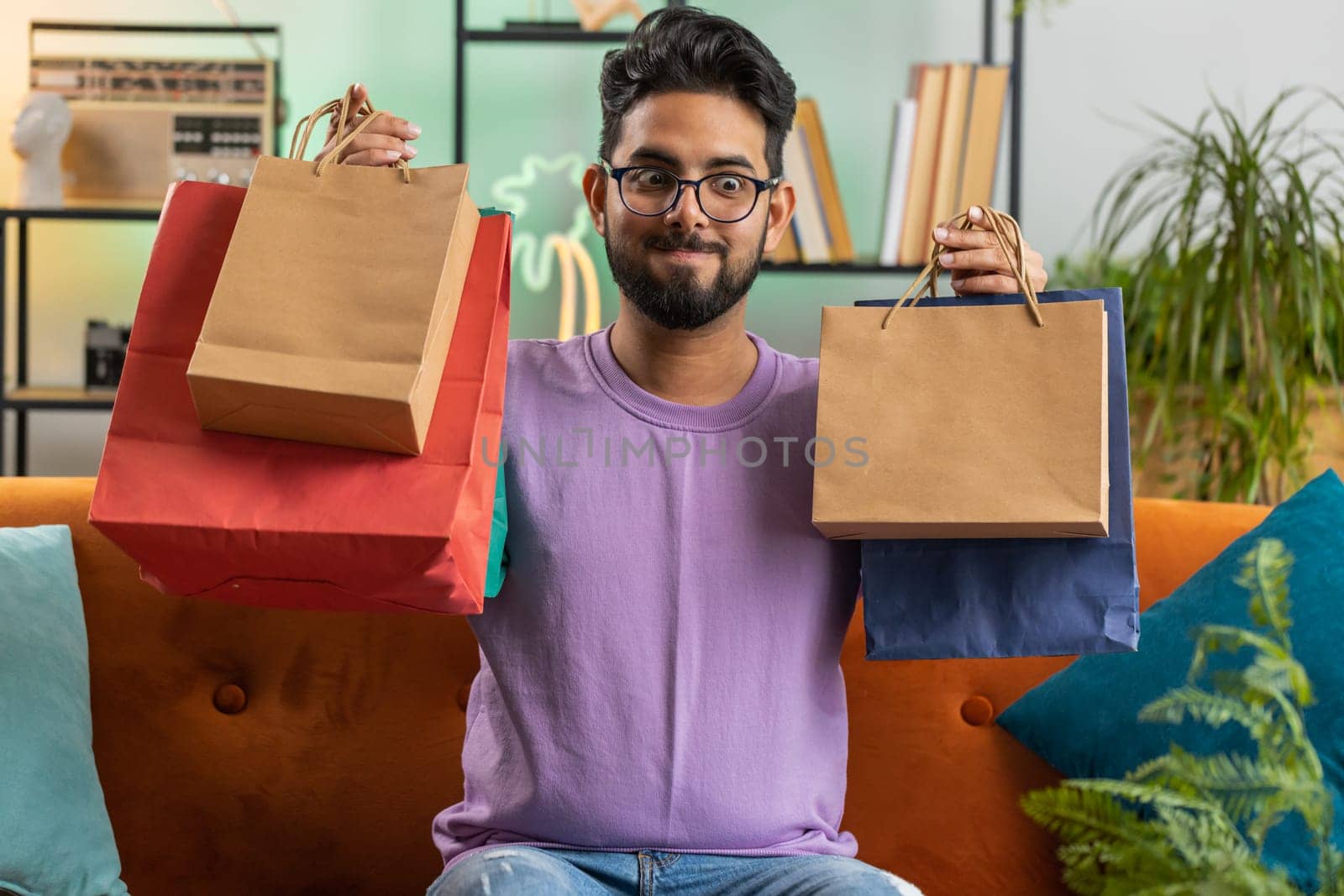 Happy indian man shopaholic consumer came back home after online shopping sale with bags at home by efuror
