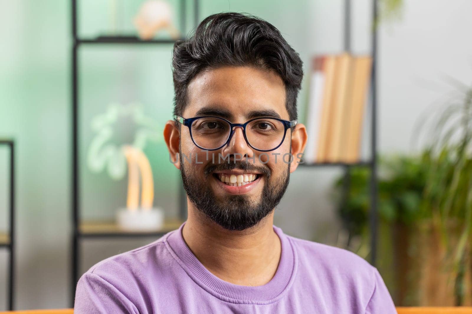 Portrait of happy calm indian man at home couch smiling friendly, glad expression looking away dreaming resting, relaxation feel satisfied concept good news, celebrate win. Hindu guy in living room
