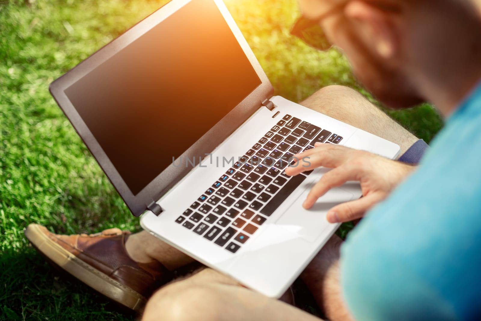 Top view male hands using notebook outdoors in urban setting while typing on keyboard, businessman freelancer working on computer while sitting on city park bench, tourist working on laptop, filter. Sun flare