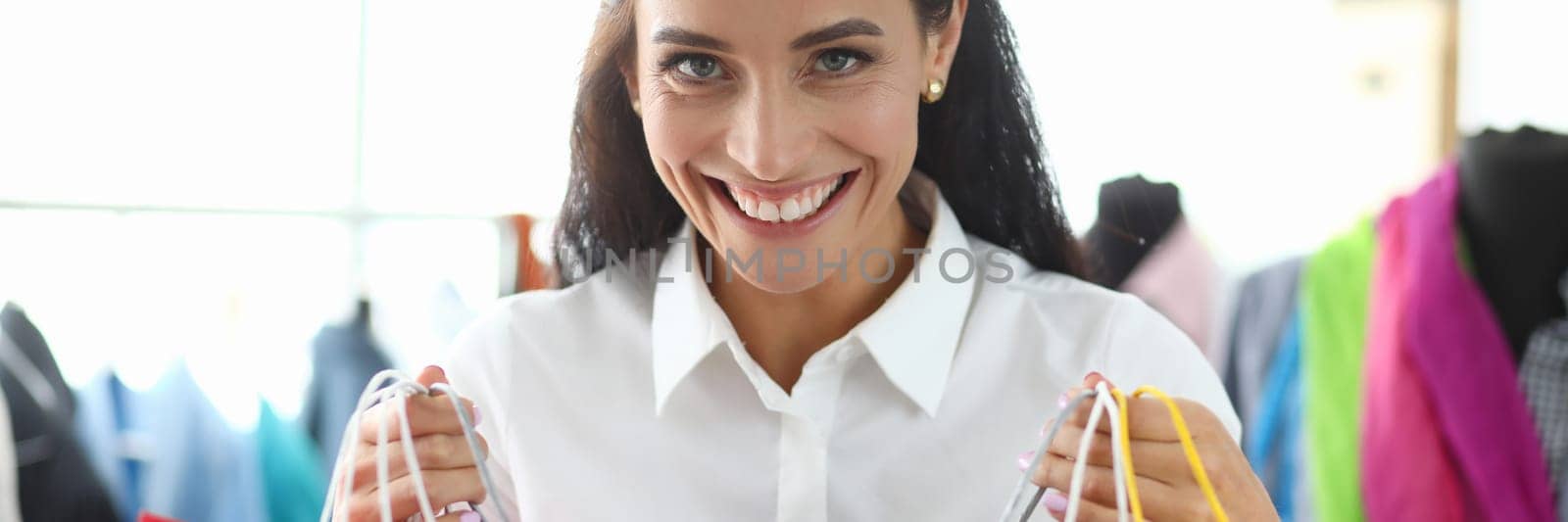 Satisfied happy woman with bright shopping bags buys packages and enjoys discounts. Girl smiling broadly showing bought gifts for holidays sale concept