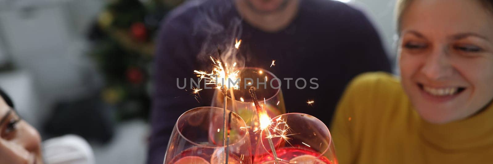 Cheerful happy people hold alcoholic cocktails with sparklers closeup by kuprevich