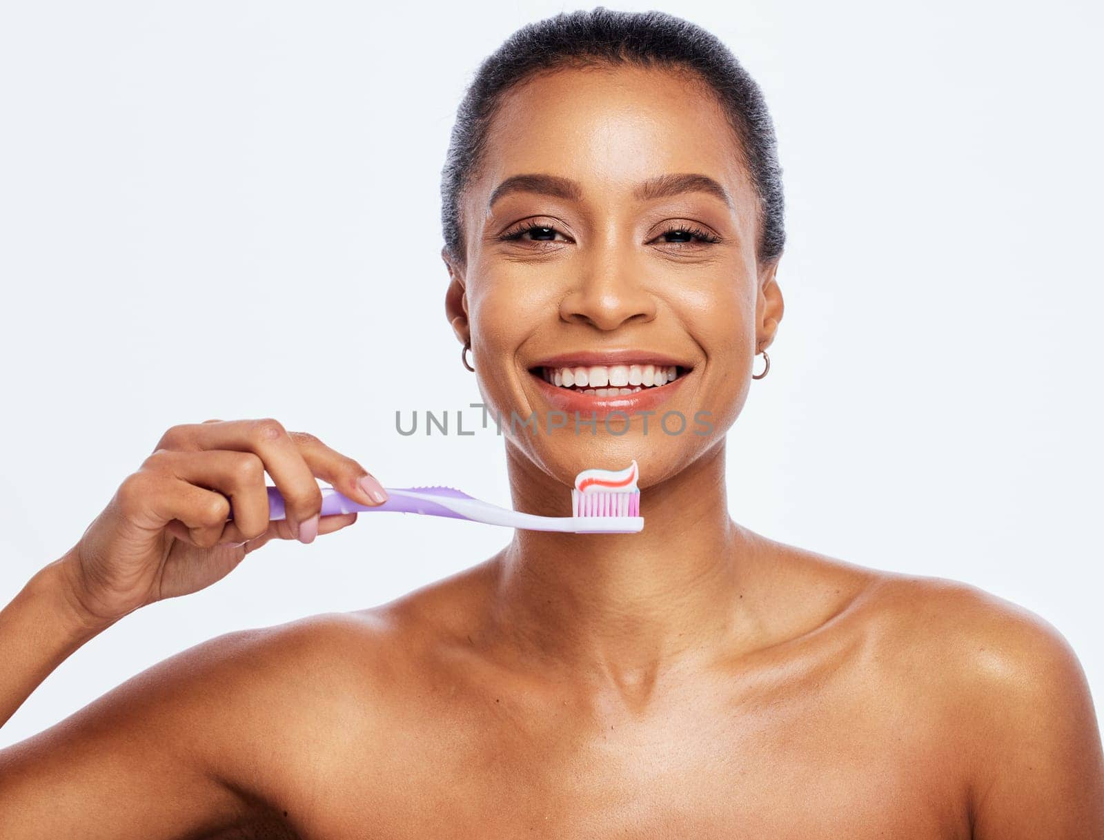 Portrait, dental and a black woman brushing teeth in studio isolated on a white background for oral hygiene. Face, toothbrush and toothpaste with an attractive young female posing on blank space by YuriArcurs