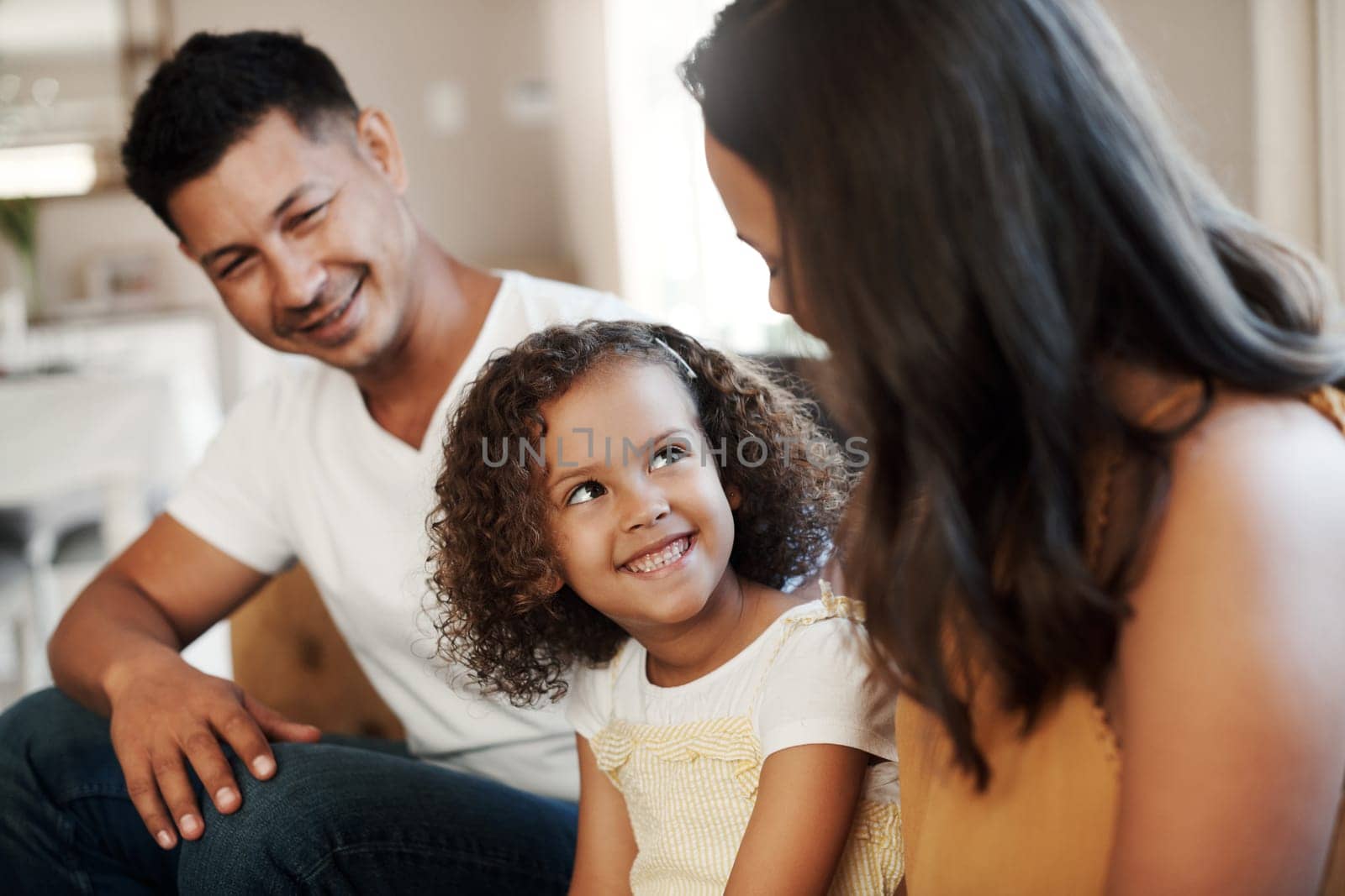 What fun things are we doing this weekend. a happy couple sitting on the sofa and bonding with their daughter at home