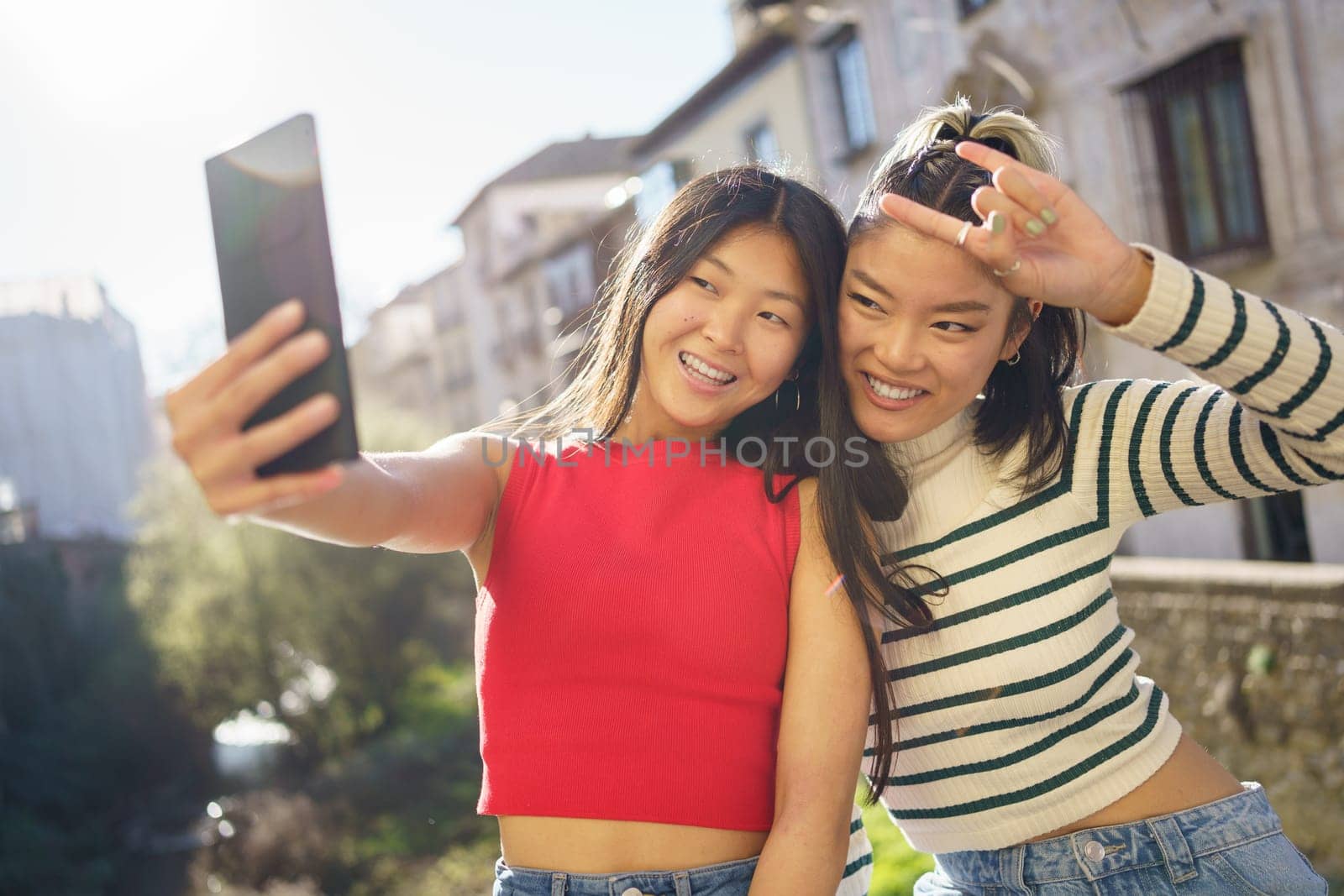 Young Asian women doing selfie together by javiindy