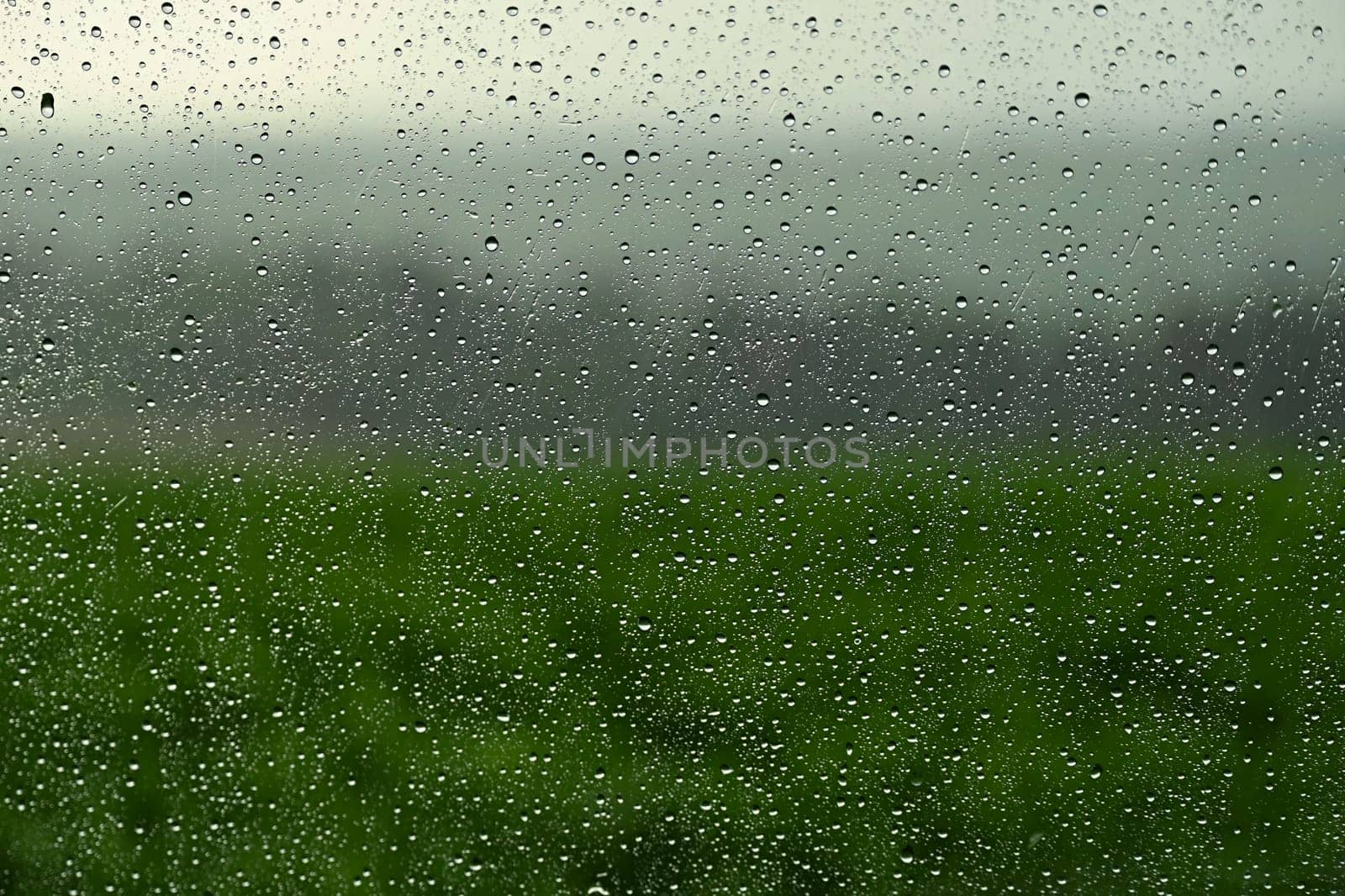 Drops on window with landscape and natural color background. Concept for rain and bad weather. by Montypeter