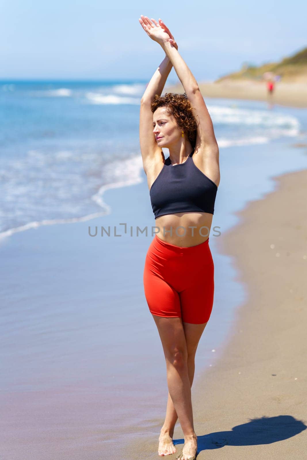 Fit woman stretching body on seashore by javiindy