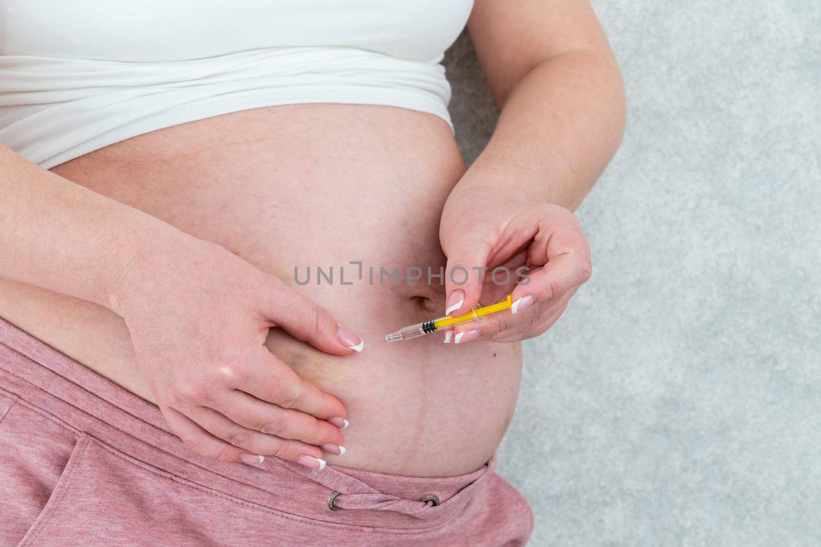Blood thinners concept. Pregnant woman making injection in stomach by Mariakray