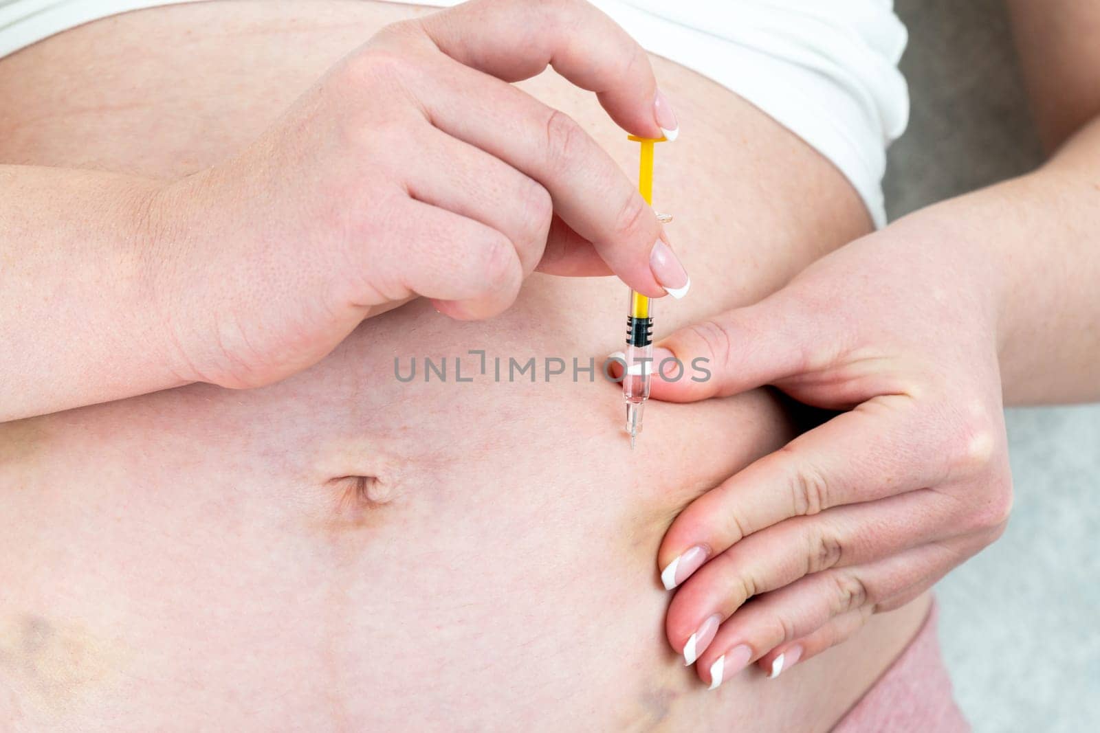 Blood thinners concept. Close up of Pregnant woman making injection in stomach by Mariakray