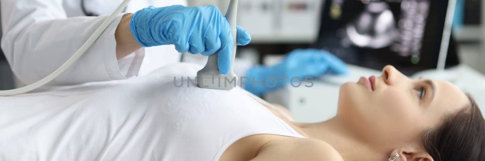 Doctor holds ultrasound probe on chest of patient in clinic closeup. Medical examination of breast in clinic