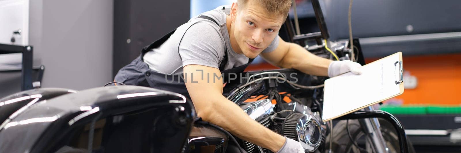 Male mechanic diagnoses modern motorcycle in service center by kuprevich