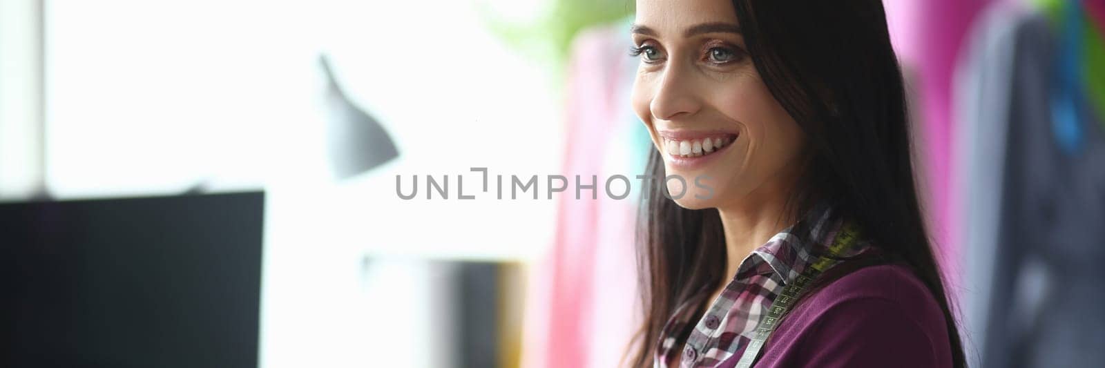 Smiling female fashion designer with scissors in hands in atelier by kuprevich