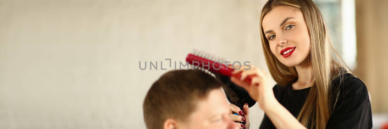 Woman in hairdresser hairdresser makes ahairstyle with hair dryer for male client. Stylish trendy hairstyle concept