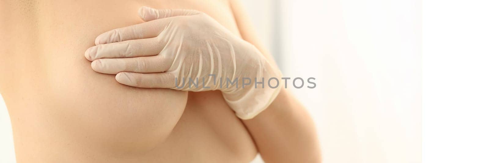 Naked woman examines breasts in gloved hands. Breast medical diagnostics concept