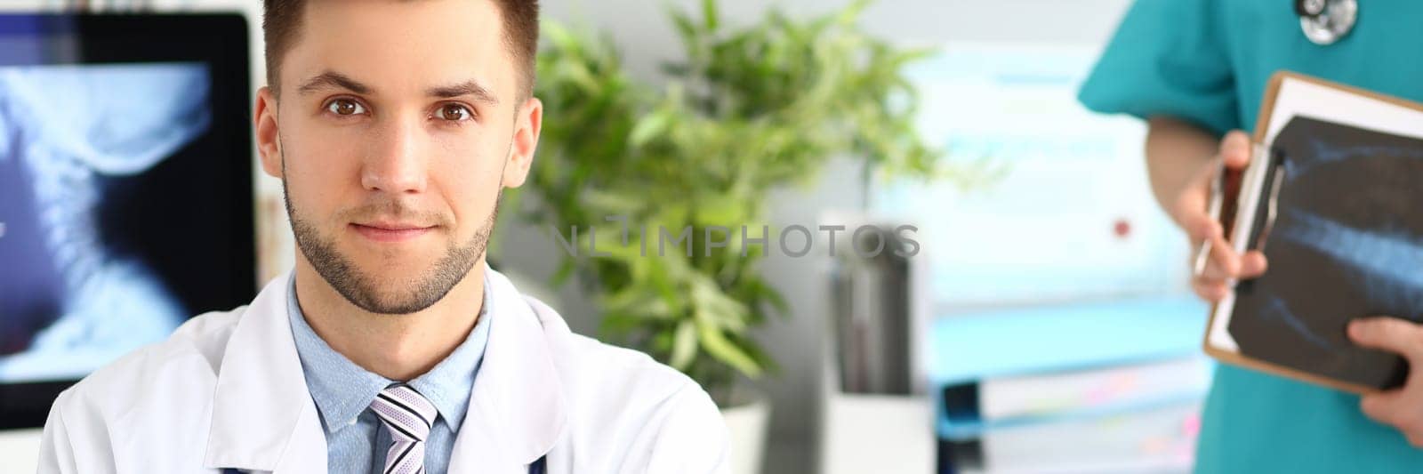 Portrait of young doctor in clinic with an assistant. Medical services and examinations of body concept