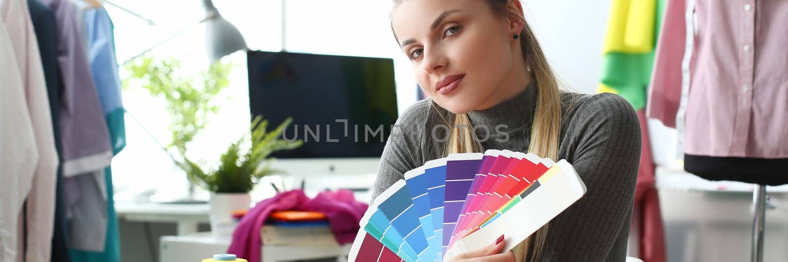 Female fashion designer seamstress working in studio holding color palette by kuprevich