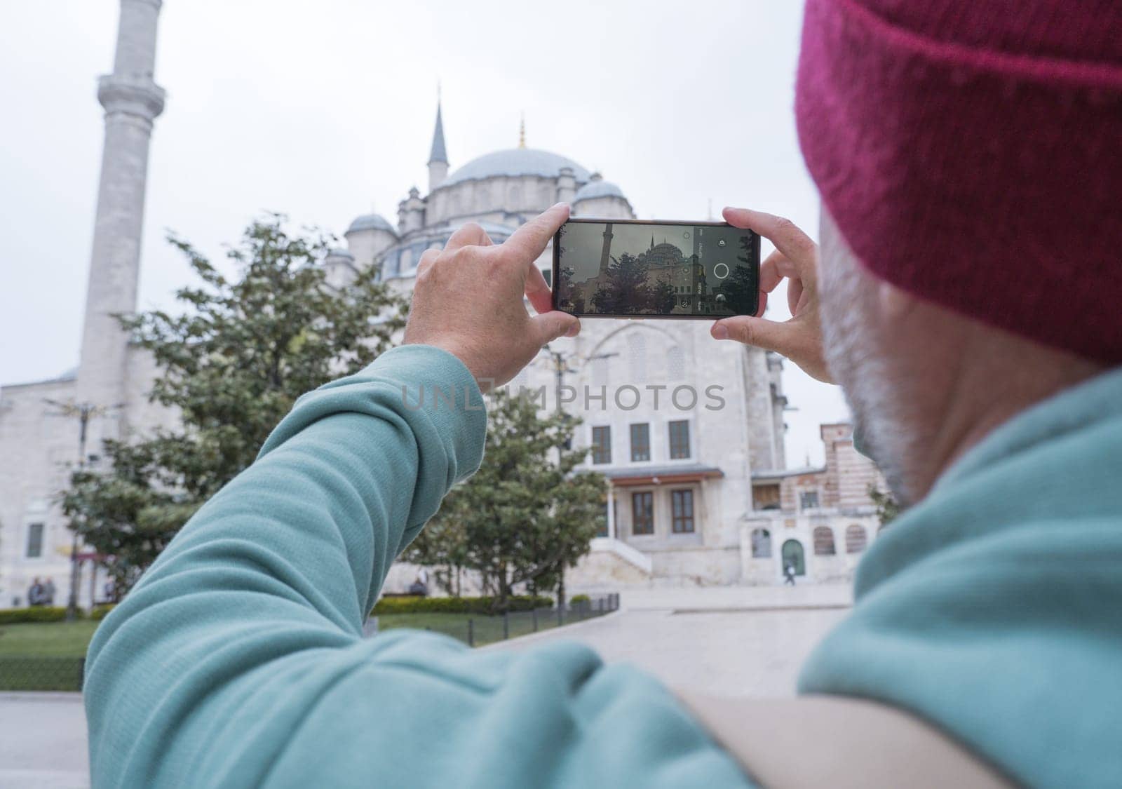 A male tourist takes a photo of the Fatih Mosque in Istanbul, Turkey as a keepsake. by Ekaterina34