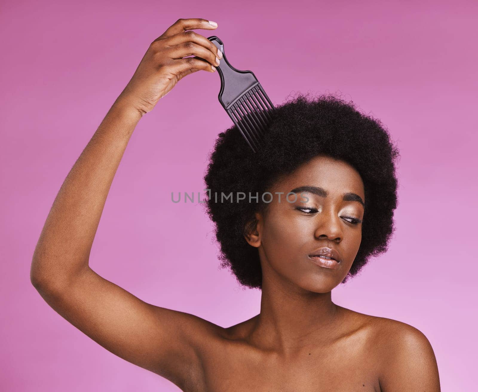 Black woman, hairstyle or afro brushing on beauty studio background in relax grooming routine, texture maintenance or wellness. Model, comb or natural hair growth and skincare makeup on isolated pink.