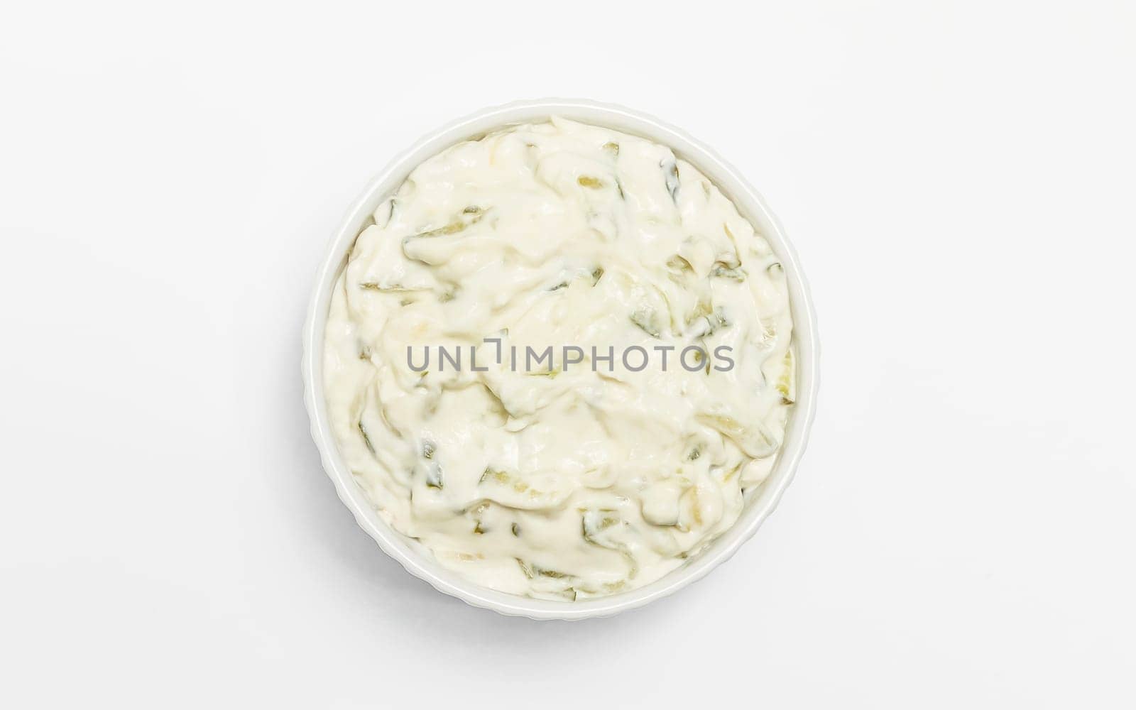 Isolated traditional greek yogurt sauce Tzatziki,dressing in white bowl, made of grated cucumbers, sour cream yogurt,olive oil,garlic,herbs on white background. Close up, flat lay, horizontal