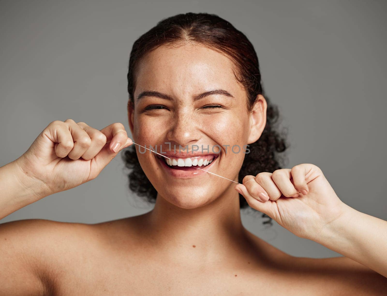 Dental floss, flossing teeth and woman with a smile for oral hygiene, health and wellness on studio background. Face of a happy female during self care, healthcare and grooming for a healthy mouth.