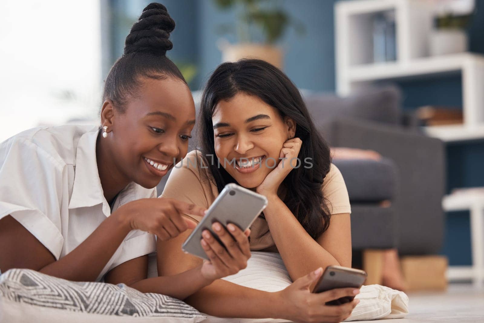 Woman, friends and phone with smile for social media, online post or vlog lying on floor in living room at home. Happy women relaxing and smiling on smartphone for communication, wifi or networking.